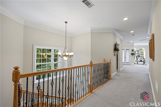 hallway featuring carpet floors, visible vents, baseboards, an inviting chandelier, and crown molding