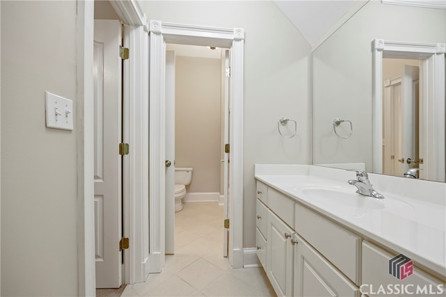 bathroom featuring baseboards, vanity, toilet, and tile patterned floors