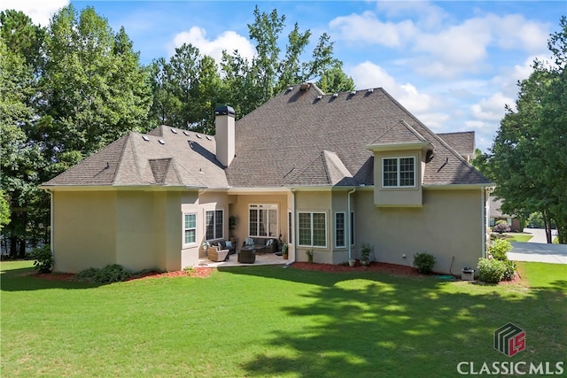 rear view of property with a lawn, a chimney, roof with shingles, a patio area, and outdoor lounge area