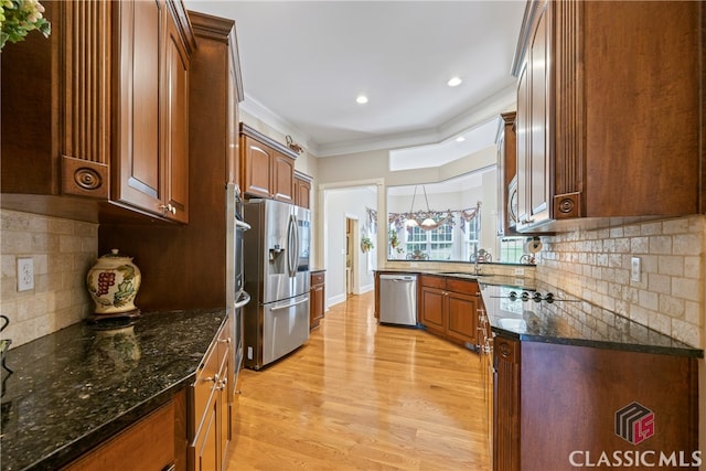 kitchen featuring backsplash, appliances with stainless steel finishes, light wood-style floors, ornamental molding, and a sink