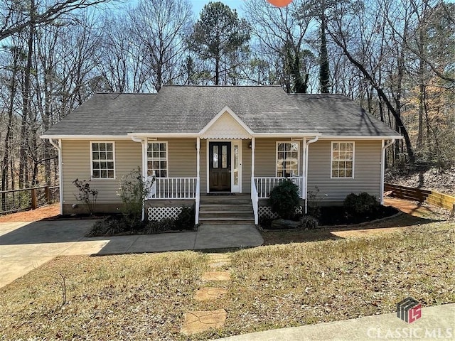 view of front of home featuring covered porch, a shingled roof, and fence