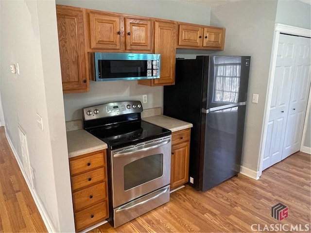 kitchen featuring appliances with stainless steel finishes, baseboards, light countertops, and light wood-style floors