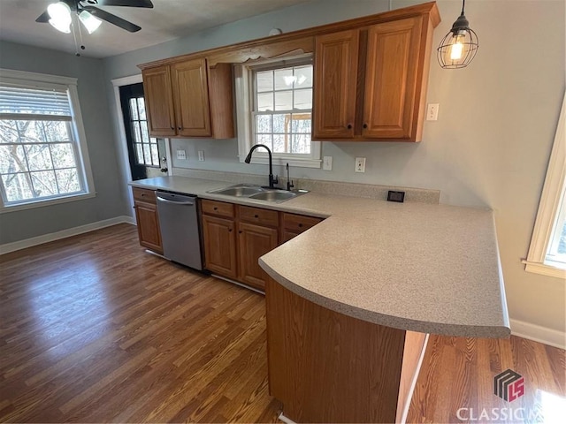 kitchen featuring stainless steel dishwasher, light countertops, brown cabinets, and a sink