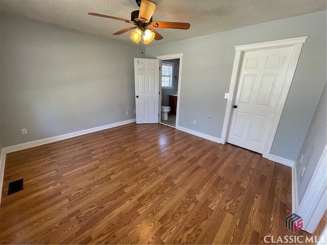 unfurnished bedroom with a textured ceiling, wood finished floors, visible vents, and baseboards