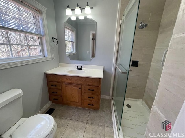 bathroom with baseboards, vanity, toilet, and a shower stall