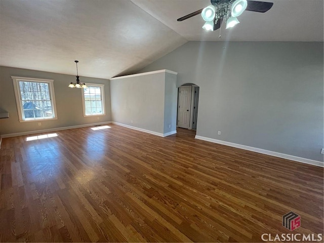 unfurnished living room featuring arched walkways, dark wood-type flooring, baseboards, and vaulted ceiling