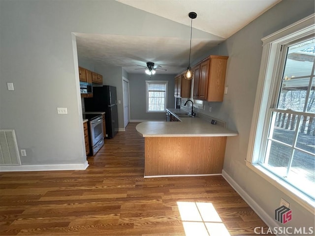 kitchen with visible vents, a peninsula, electric range, a sink, and brown cabinets