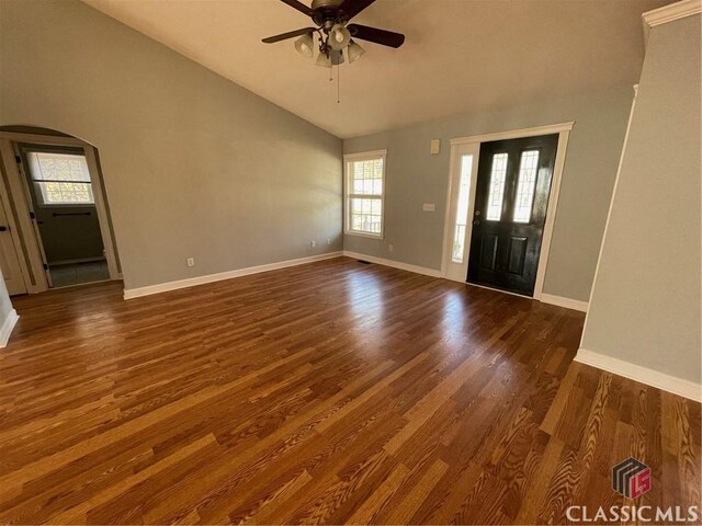 foyer entrance with arched walkways, dark wood finished floors, and baseboards