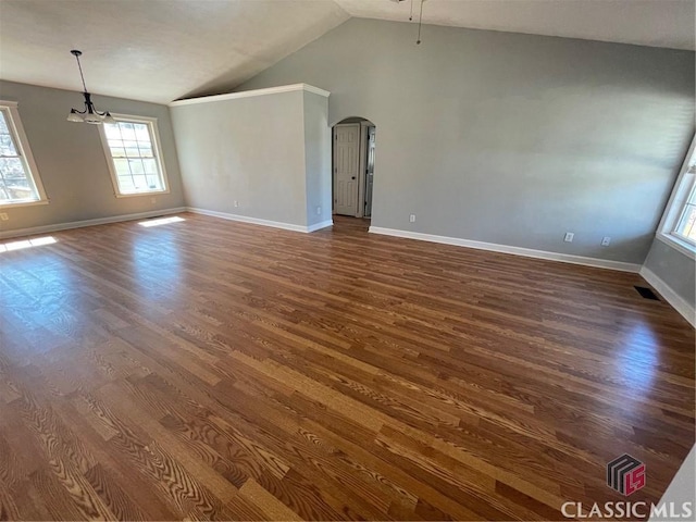 unfurnished living room with visible vents, baseboards, dark wood finished floors, lofted ceiling, and arched walkways