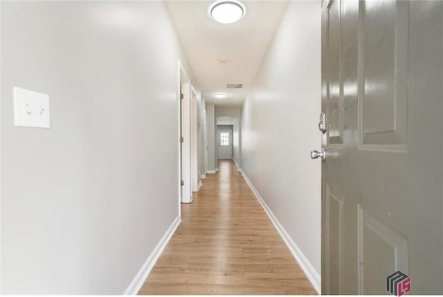 corridor featuring light wood-type flooring and baseboards