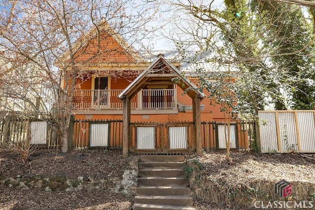 view of front of house featuring a balcony and fence