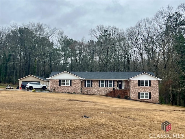 view of front of house featuring a front lawn, brick siding, and an outdoor structure