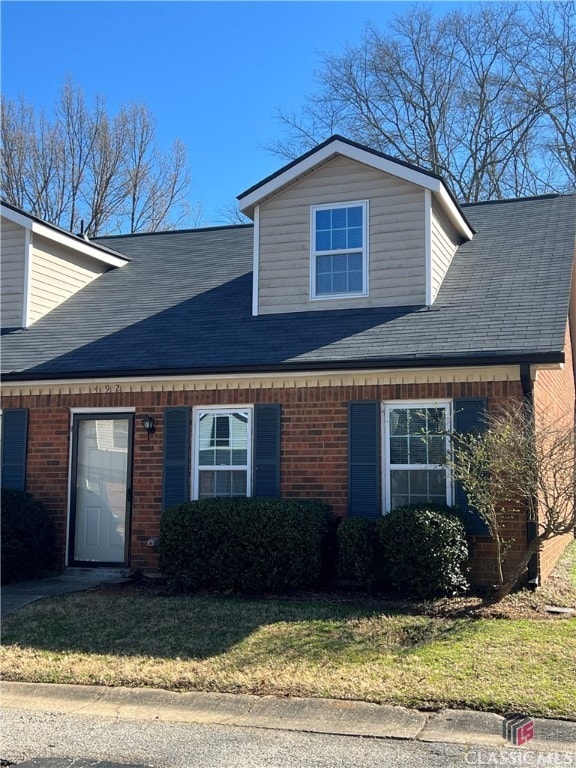 view of home's exterior featuring a yard, brick siding, and a shingled roof