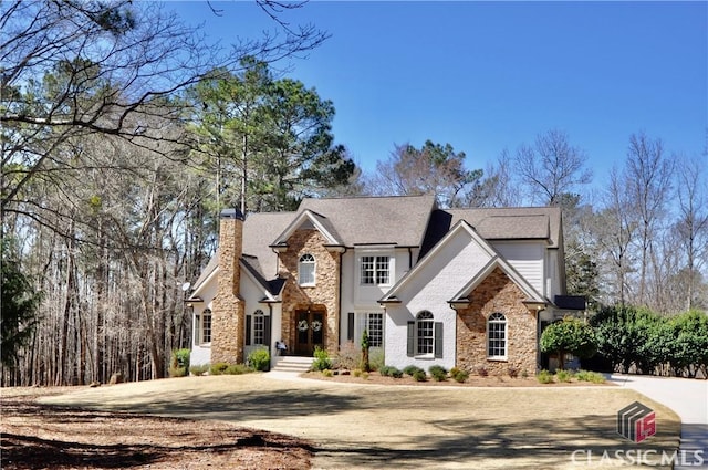 french country home featuring stone siding and a chimney