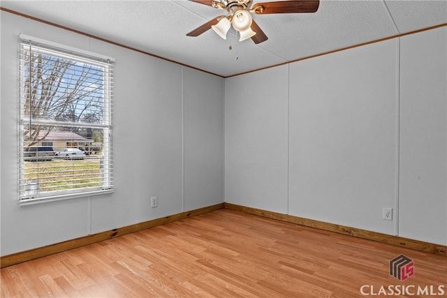 empty room with light wood finished floors, a textured ceiling, crown molding, and a ceiling fan