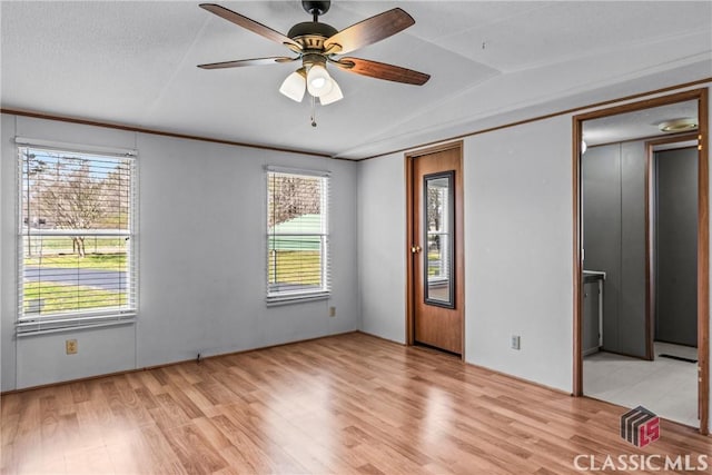 unfurnished bedroom with multiple windows, light wood-type flooring, and lofted ceiling