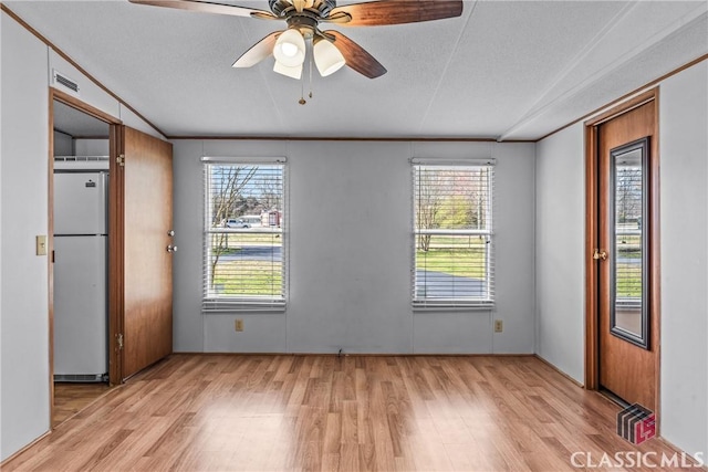 spare room with light wood-type flooring, visible vents, ornamental molding, a ceiling fan, and a textured ceiling