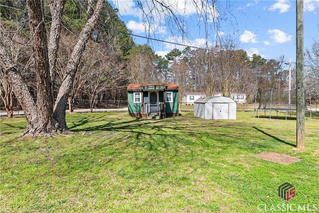 view of yard with a storage unit, a trampoline, and an outdoor structure