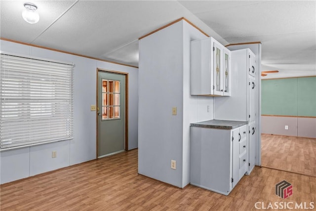 kitchen featuring glass insert cabinets, light wood-style floors, white cabinets, and ornamental molding