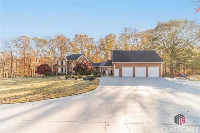 view of front of home featuring brick siding, driveway, an attached garage, and a front yard