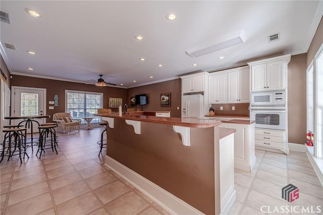kitchen with visible vents, crown molding, a large island with sink, and white appliances