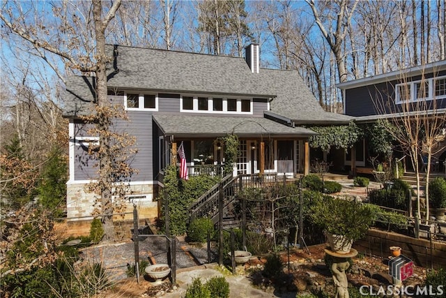 view of front of property featuring roof with shingles, a chimney, and stairs