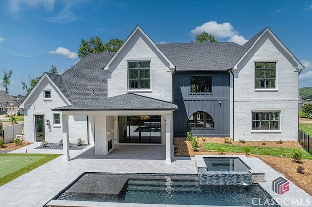 rear view of house with a patio, fence, an in ground hot tub, decorative driveway, and board and batten siding