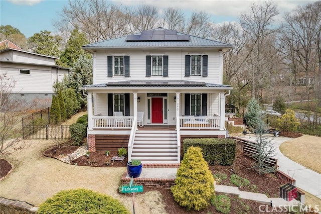 traditional style home with a porch, fence, metal roof, solar panels, and stairs