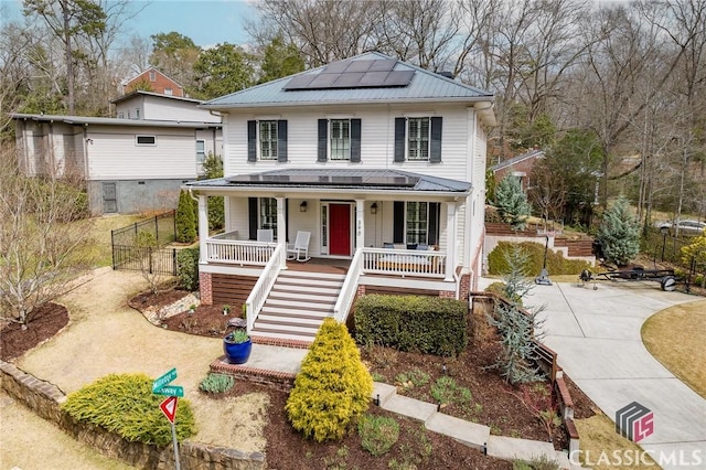 view of front of property with solar panels, fence, a porch, stairs, and metal roof