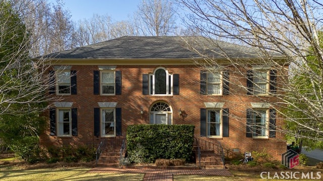 view of front facade with brick siding, crawl space, and roof with shingles