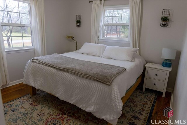 bedroom featuring baseboards, multiple windows, and wood finished floors