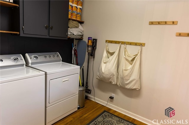 washroom with washer and dryer, baseboards, cabinet space, and dark wood finished floors