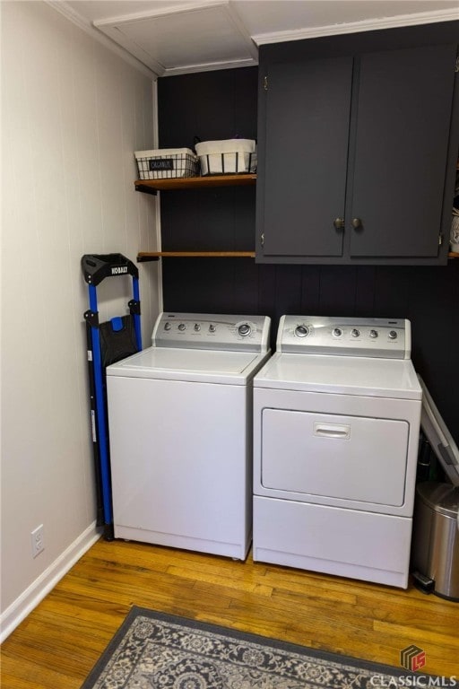 washroom with wood finished floors, cabinet space, baseboards, and washer and clothes dryer