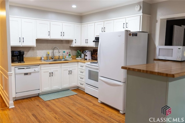 kitchen featuring light wood finished floors, white cabinets, white appliances, and a sink