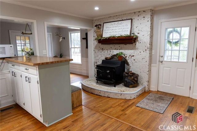 kitchen with visible vents, wooden counters, white microwave, and white cabinetry