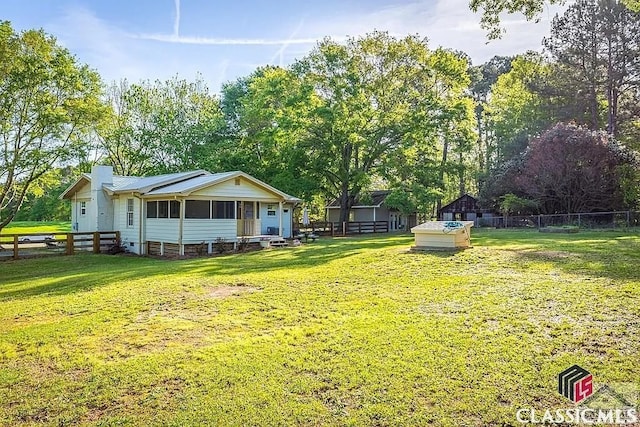 view of front facade featuring a chimney, a sunroom, a front lawn, and fence