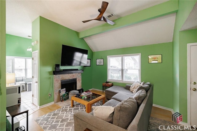 living area with a tiled fireplace, visible vents, plenty of natural light, and lofted ceiling with beams