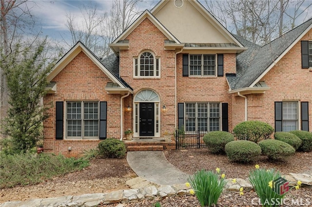 view of front of property with brick siding, stucco siding, and roof with shingles