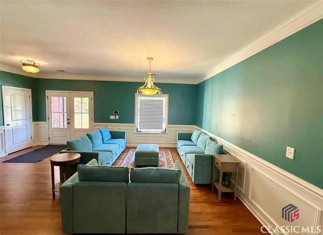 living room with ornamental molding, wood finished floors, and wainscoting