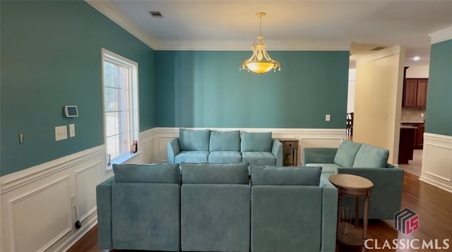 living room featuring visible vents, dark wood-style flooring, ornamental molding, wainscoting, and a decorative wall