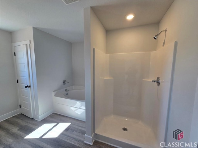 bathroom featuring baseboards, walk in shower, wood finished floors, and a bath