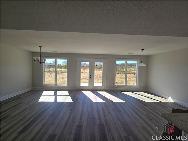 unfurnished living room featuring an inviting chandelier, dark wood-style floors, baseboards, and a textured ceiling