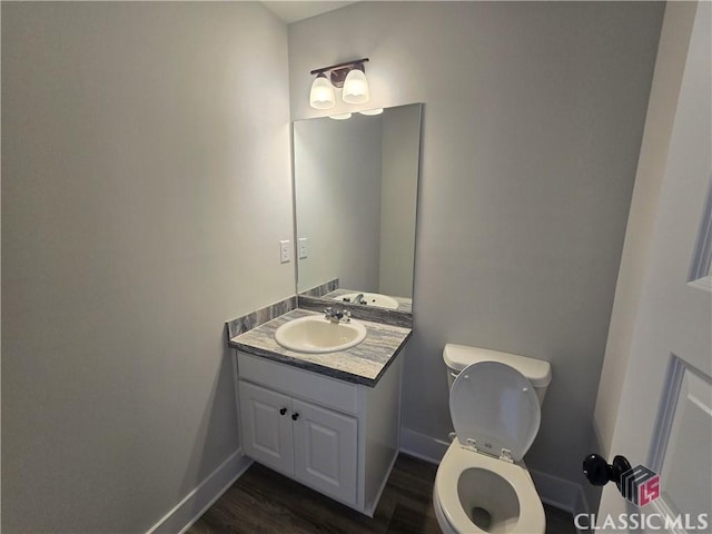 bathroom featuring toilet, vanity, baseboards, and wood finished floors