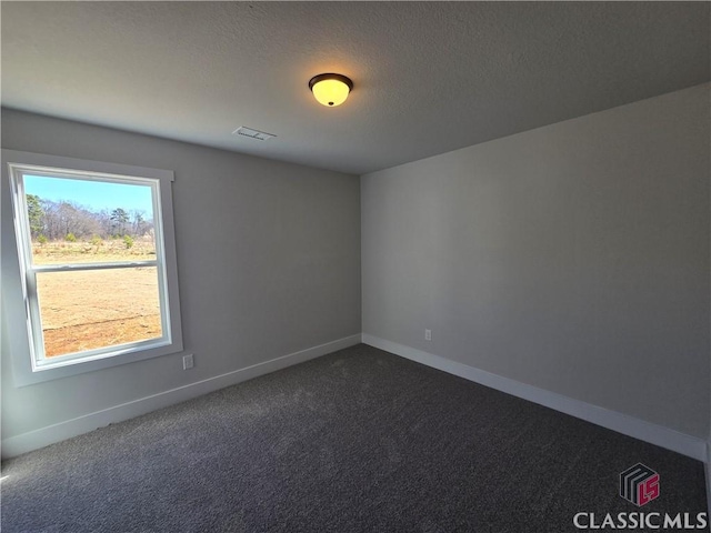 unfurnished room with dark colored carpet, visible vents, baseboards, and a textured ceiling