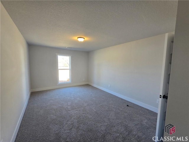 empty room featuring a textured ceiling, baseboards, and carpet