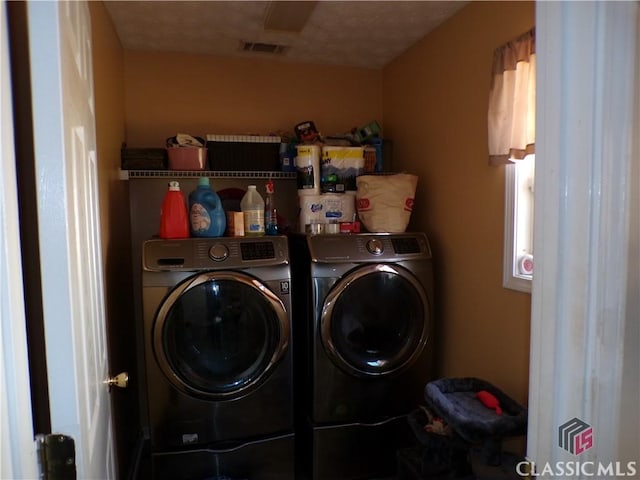 clothes washing area featuring laundry area, visible vents, and washer and clothes dryer