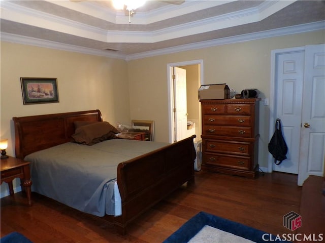 bedroom with a raised ceiling, crown molding, and dark wood-type flooring