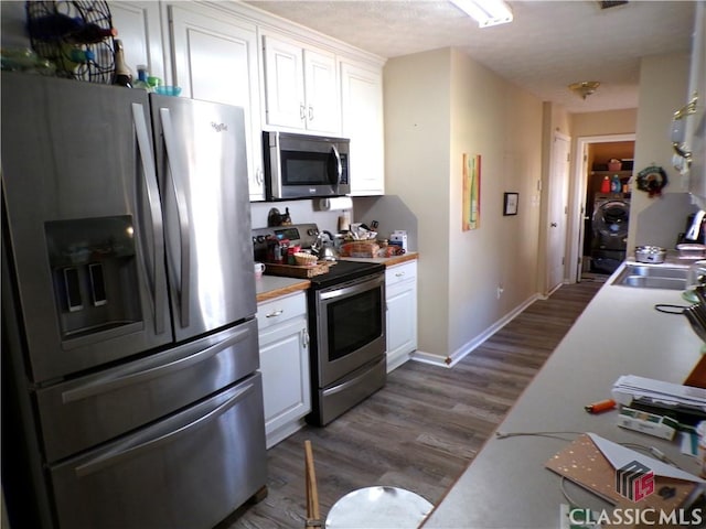 kitchen with a sink, dark wood-style floors, stainless steel appliances, white cabinets, and light countertops