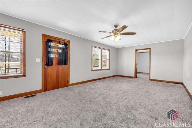 carpeted empty room with visible vents, baseboards, and ceiling fan