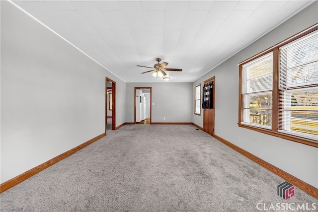 carpeted spare room featuring ceiling fan and baseboards